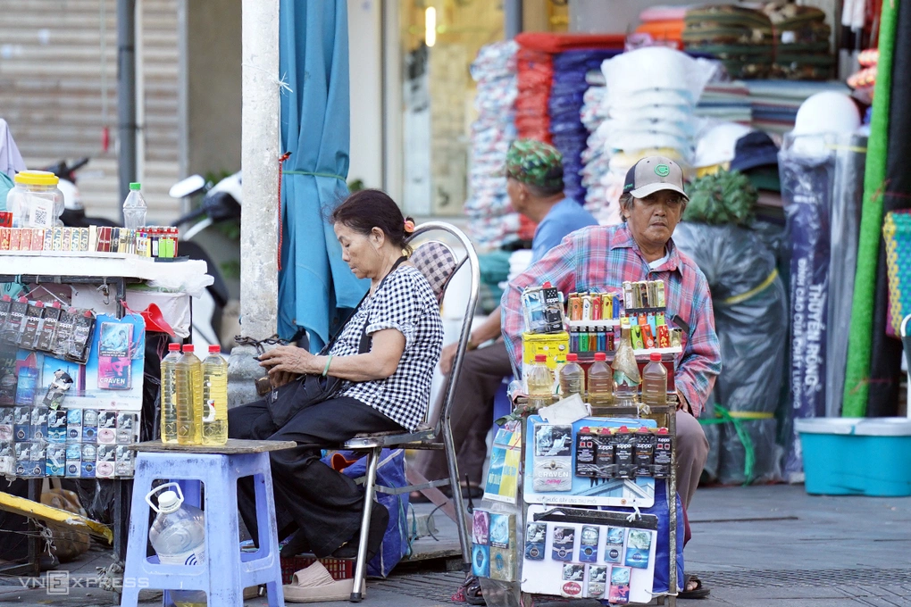Để bám trụ vỉa hè mưu sinh, nhiều người buôn bán phải co kéo sạp hàng nhỏ lại để nhường lối cho người đi bộ. Ảnh: Nguyễn Đông
