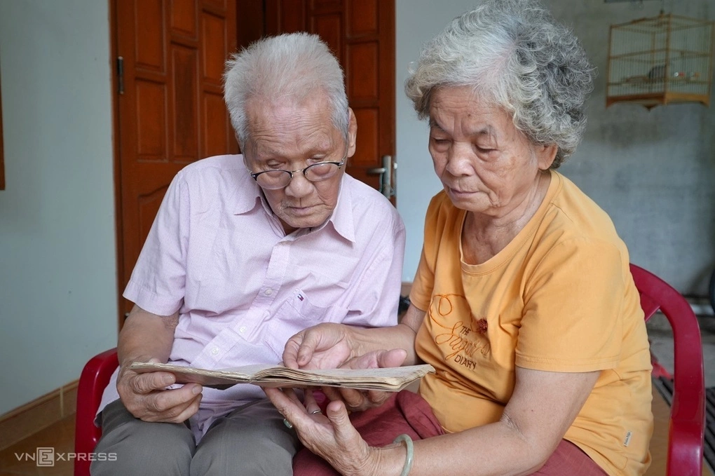 Ông Đào Ngọc Thạnh và vợ là bà Mai Thị Kim Ngân xem lại những trang ghi ghép về các chiến sĩ hi sinh trong cuốn sổ đã gìn giữ hơn nửa thế kỷ. Ảnh: Phạm Linh