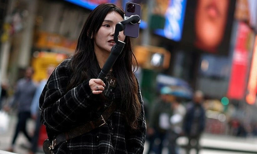 Một phụ nữ quay video để đăng lên TikTok tại Quảng trường Thời đại ở New York, Mỹ, ngày 13/3/2024. Ảnh: Reuters